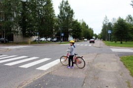 Ennen kadun ylitystä pyöräilijän pitää hypätä pois pyörän selästä ja katsoa tarkkaan molempiin suuntiin, ettei autoja tai muita ajoneuvoja ole tulossa. Elviira Luontomaa näyttää mallia. Kuva: Tiina Naula