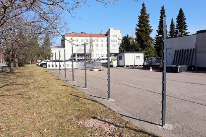 Rakennettava aita rajautuu poliisiaseman takapihan nurmialueeseen. Tolpat ovat jo pystyssä aitaelementtejä varten. Kuva: Iiro Salmi, Pasi Salo.